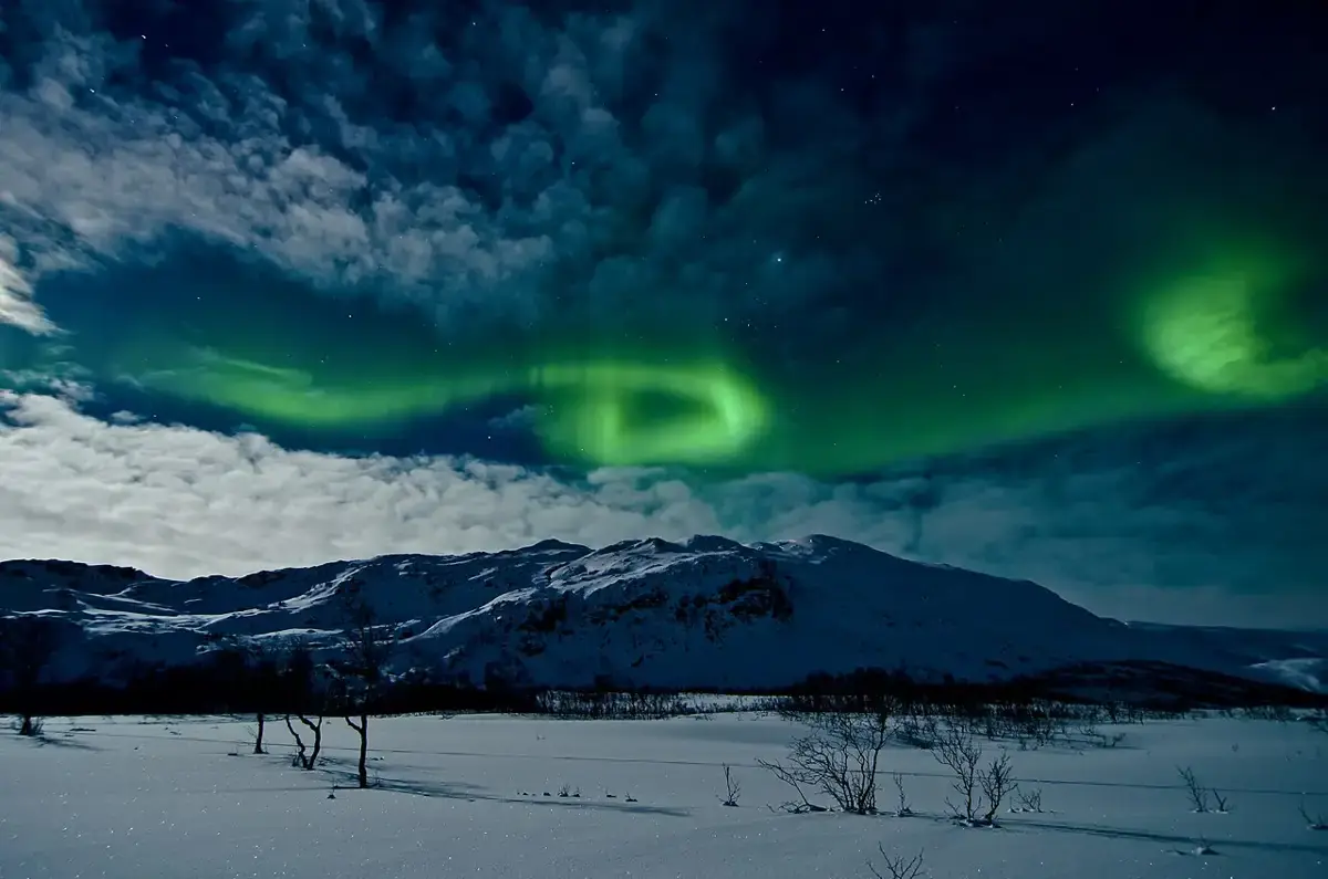 Nordlys over snødekte fjell ved Tromsø